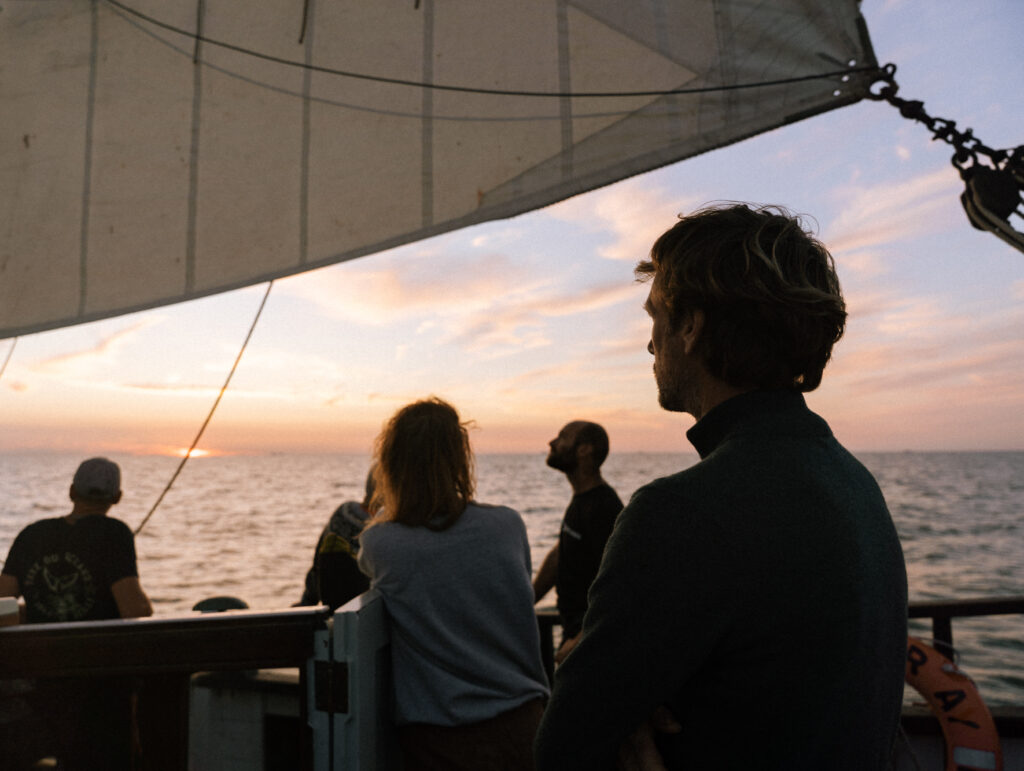 crew on board sailing vessel GRAYHOUND watching the sunset